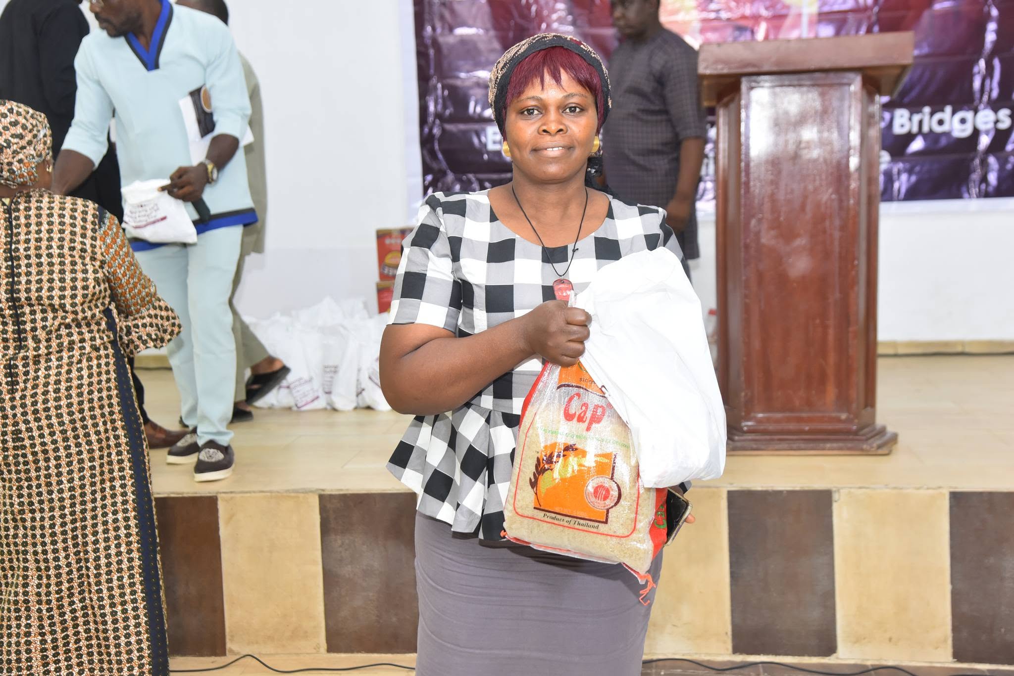 A smiling community member receiving food provisions—including a carton of instant noodles and bagged supplies—during the Prayer of Hannah Foundation empowerment and welfare outreach program.
